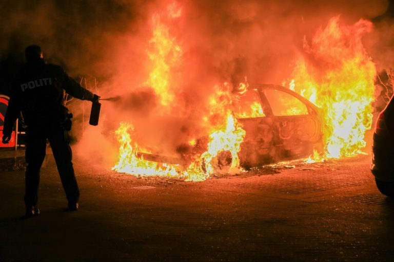 Police officer is seen putting out a fire, equipped with protective gear and a fire extinguisher